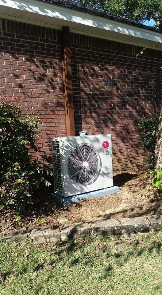 An lg air conditioner is sitting on the side of a brick building.