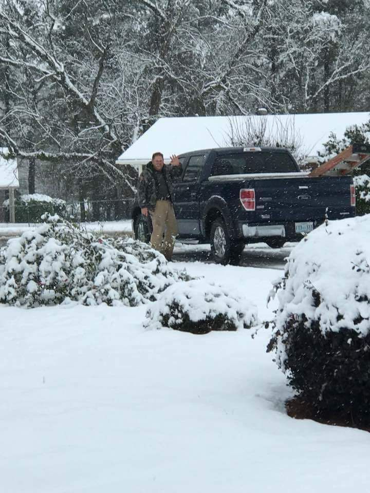 A man is standing next to a truck in the snow.