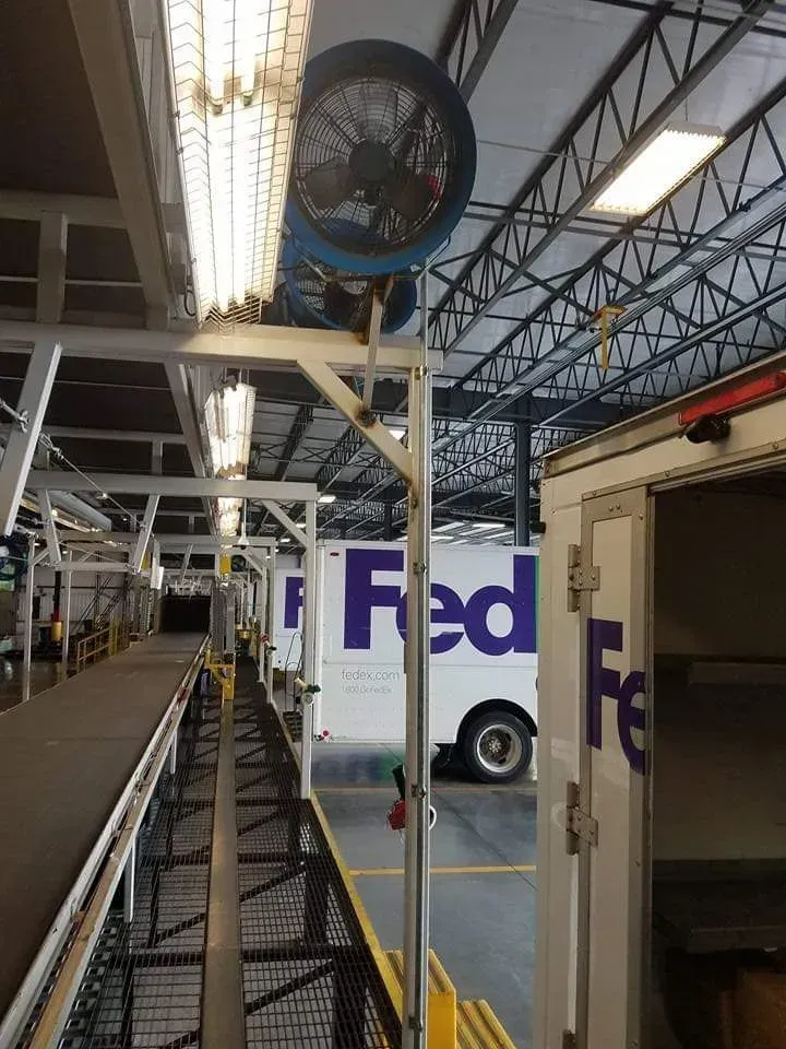 A fedex truck is parked in a warehouse next to a conveyor belt.