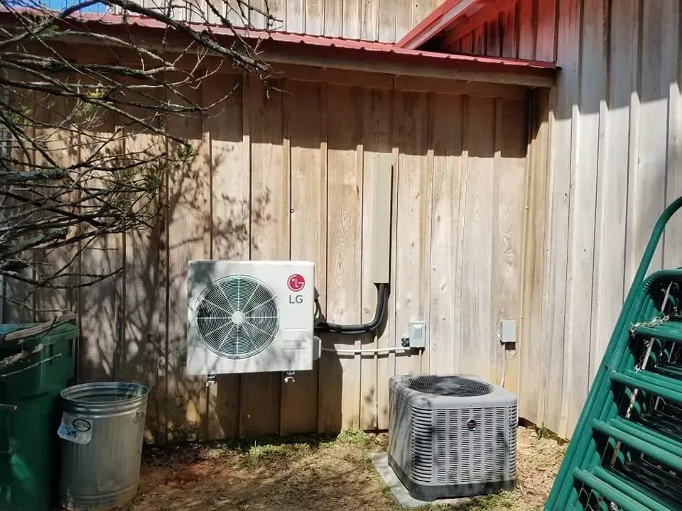 An lg air conditioner is mounted on the side of a wooden building.