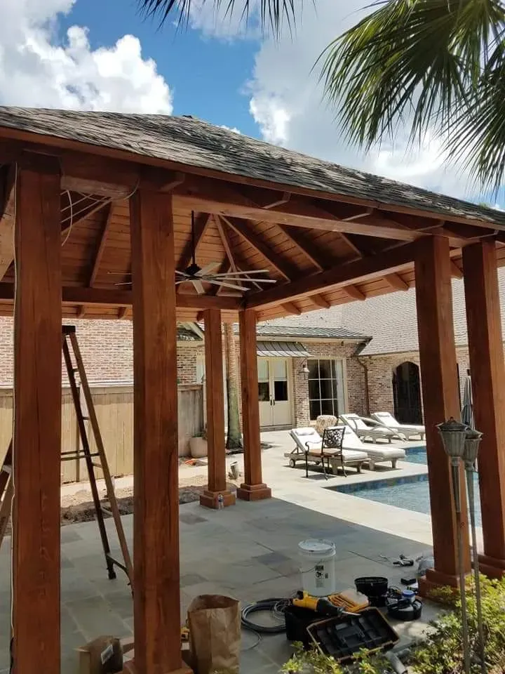 A wooden gazebo is being built next to a swimming pool.