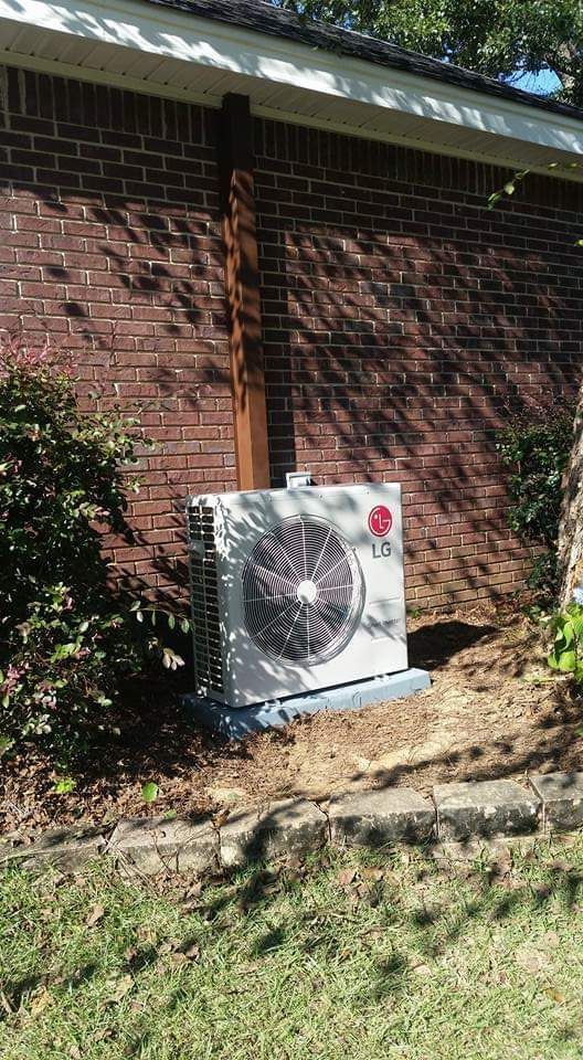 An lg air conditioner is sitting on the side of a brick building.
