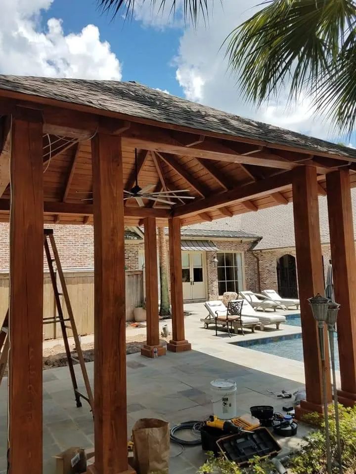 A wooden gazebo is being built next to a swimming pool.