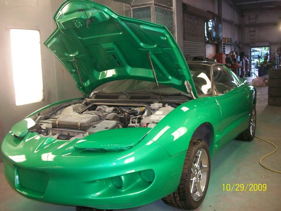 Bright green sports car with hood open in a garage, showing the engine.