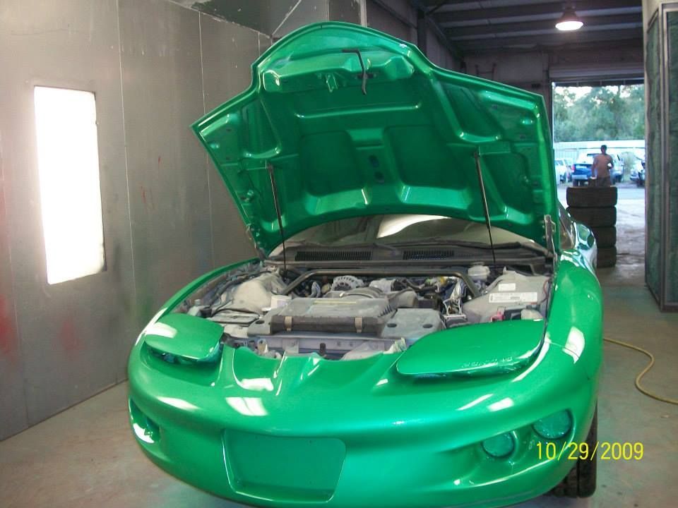 Bright green car with hood open in an auto body shop or garage
