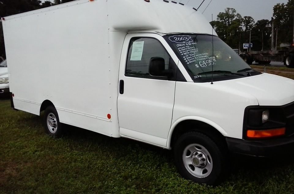 White cargo van parked on grass, side view with writing on the windshield.