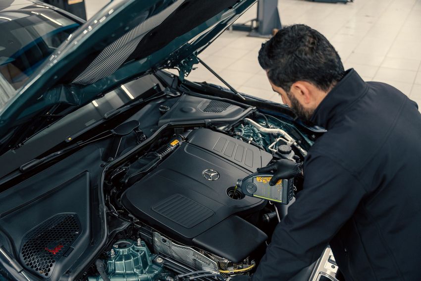 Mechanic inspecting a car engine under the open hood in a garage