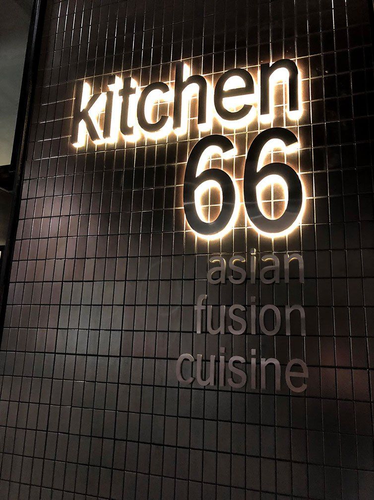 Black Logo With Yellow Backlight On A Black Brick Wall — Signage In Acacia Ridge, QLD