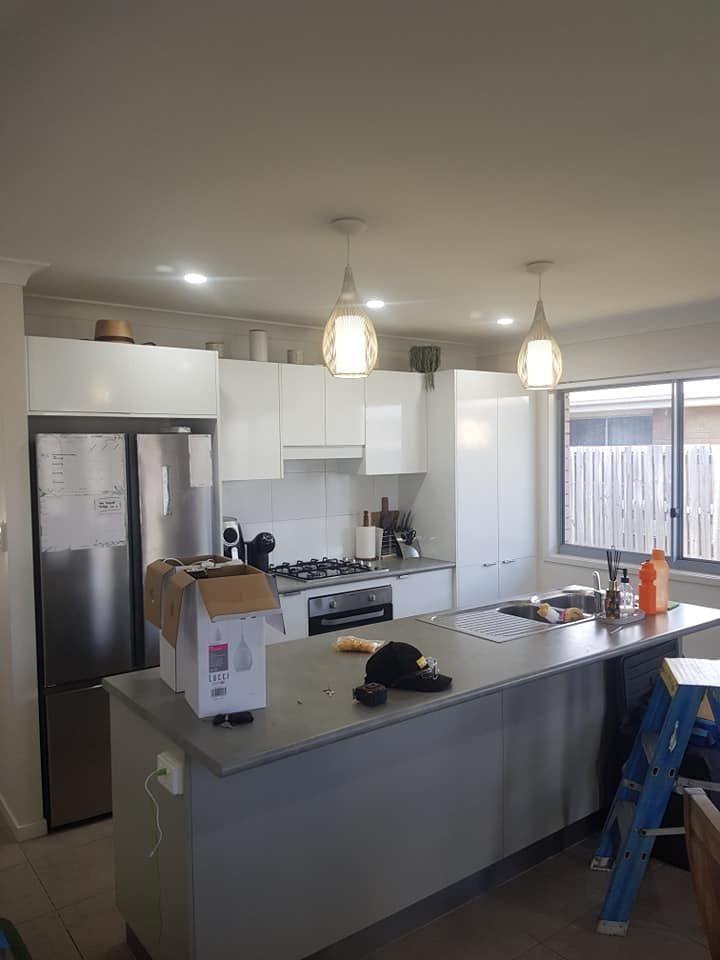 A Kitchen With White Cabinets, Stainless Steel Appliances, And A Large Island — Prowire Services In Walkerston, QLD