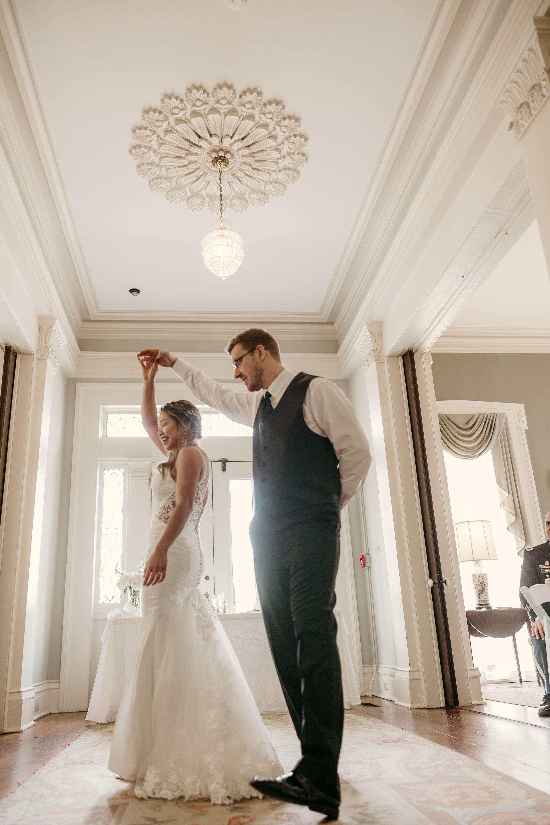 A bride and groom are kissing in front of a large white building.