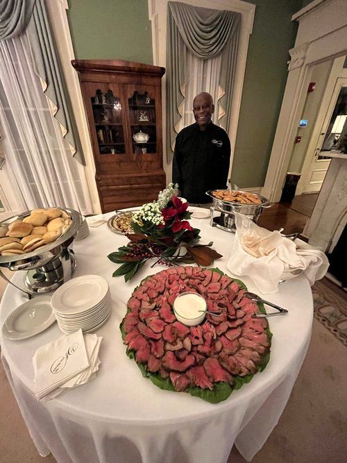 A man is standing in front of a table with food on it.