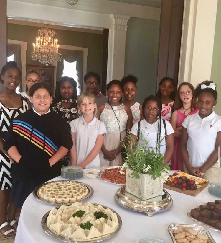 A group of children standing around a table with food on it