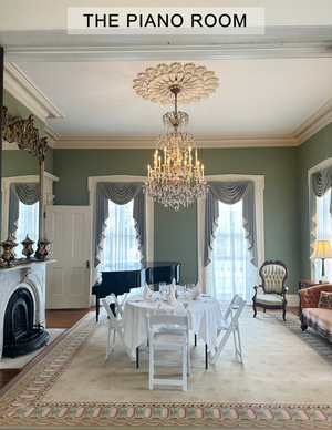 There is a piano in the piano room with a chandelier hanging from the ceiling.