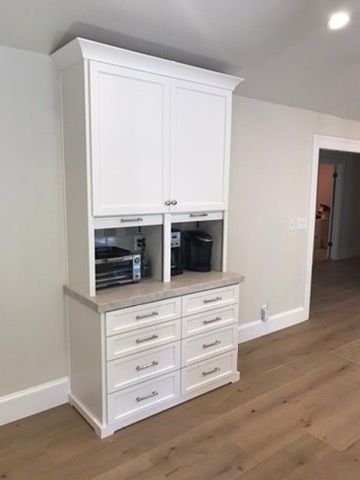 A white wooden hutch featuring a countertop, four open-front storage sections for appliances, and eight stacked drawers.