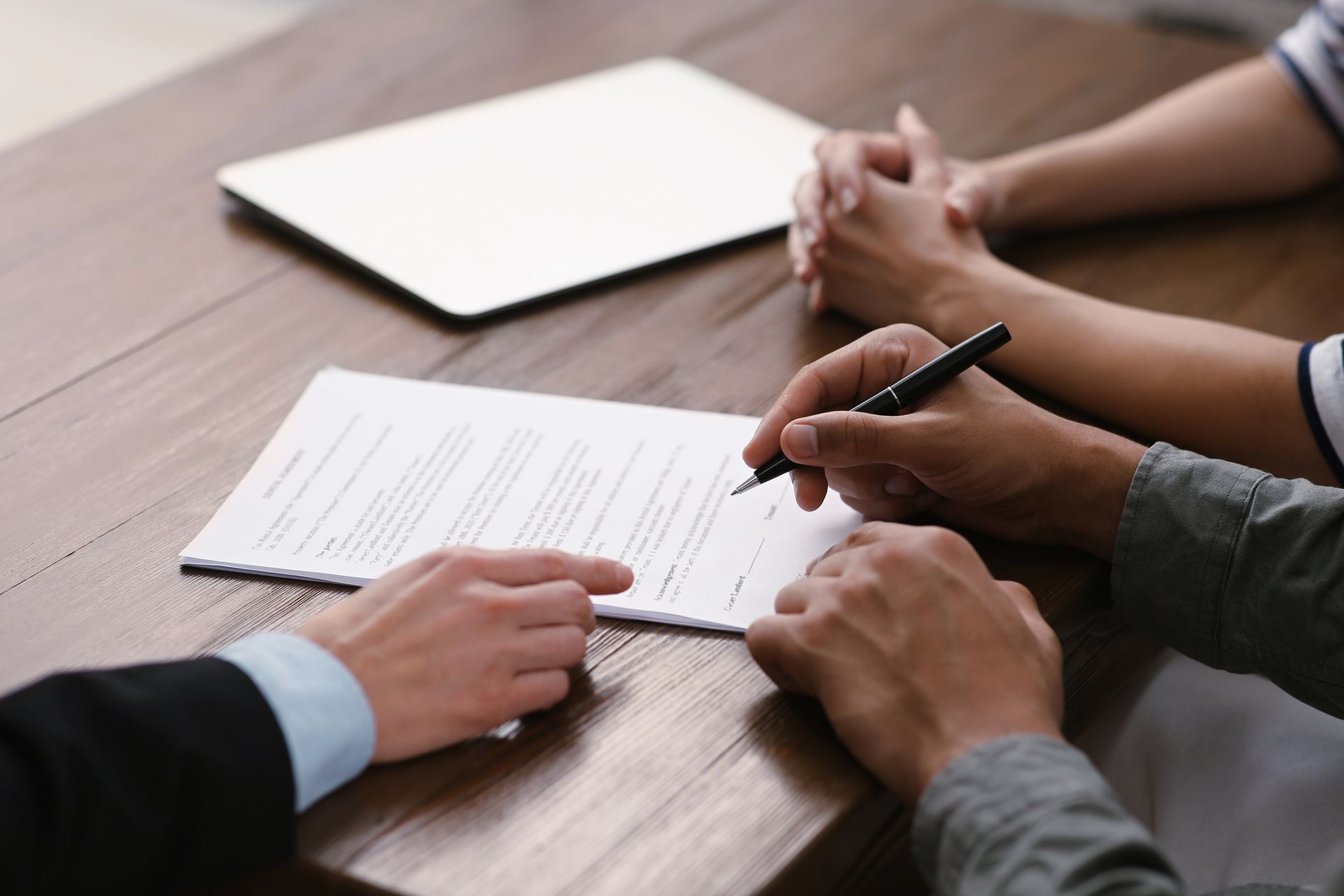 A man and a woman are sitting at a table signing a document.