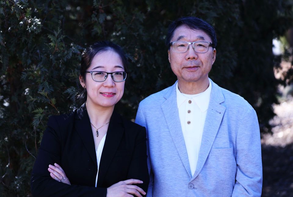 A man and a woman are standing next to each other in front of a tree.