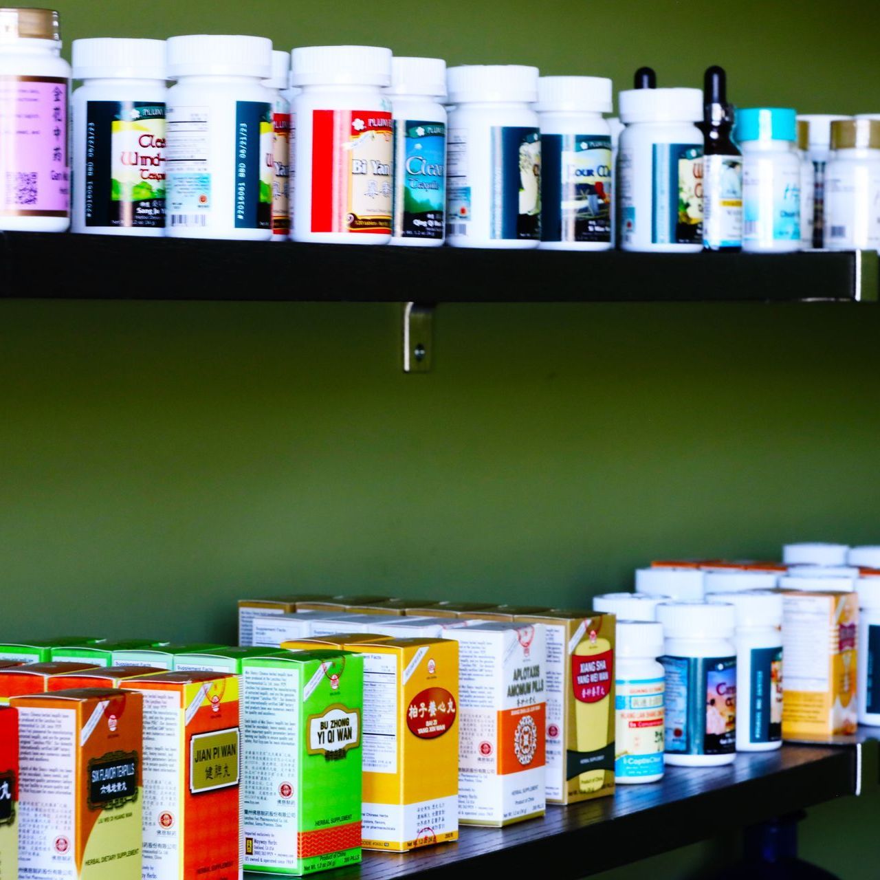 A shelf filled with lots of bottles and boxes of medicine