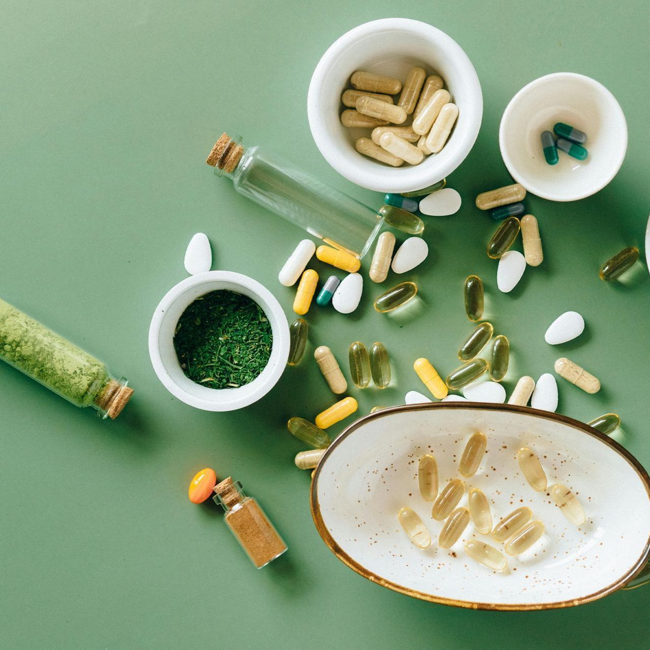 A variety of pills and bottles on a green table