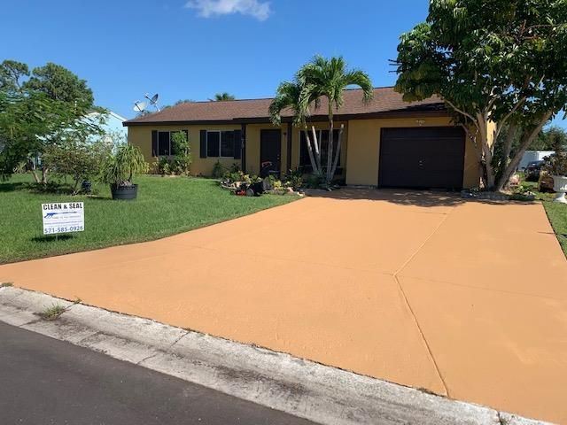 A house with a large driveway and a sign in front of it.