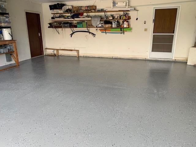 A large empty garage with a gray floor and shelves.
