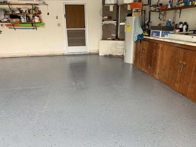 A garage with a gray floor and wooden cabinets.