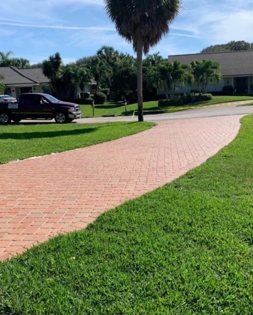 A car is parked on the side of the road next to a brick walkway