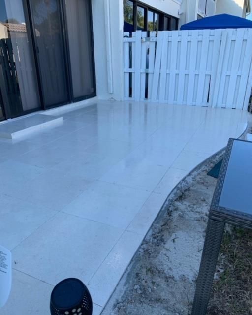A white patio with a white fence and a table