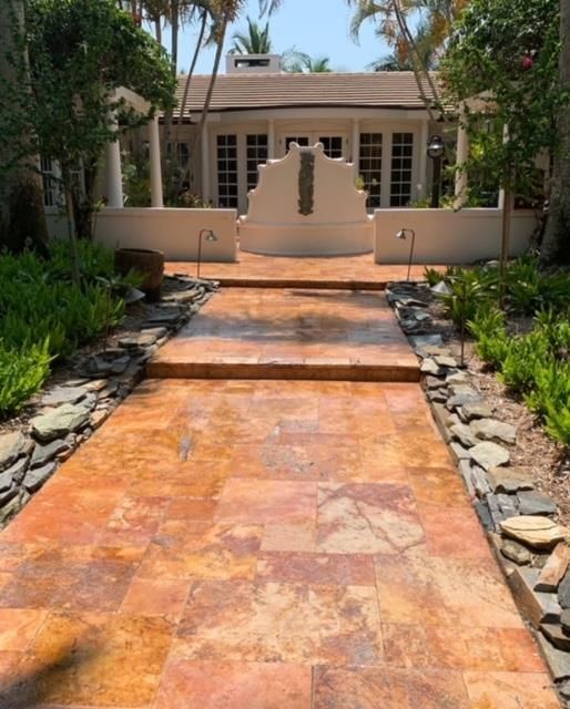 A stone walkway leading to a house with palm trees