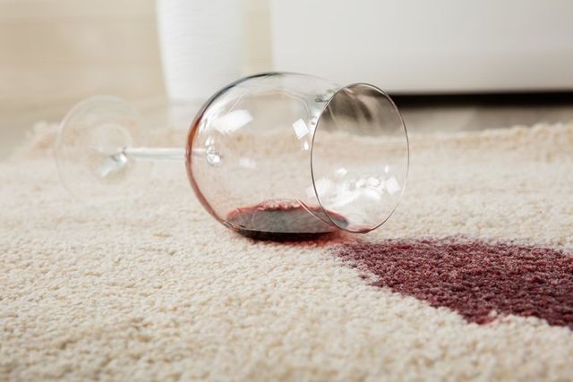 A glass of wine spilled on a carpet.