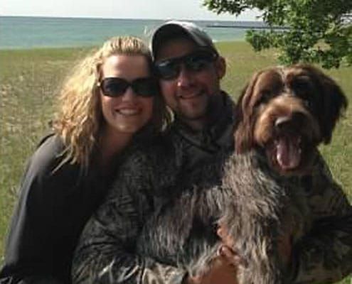 A man and a woman are posing for a picture with their dog.