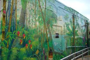 There is a mural on the side of a building that looks like a jungle.