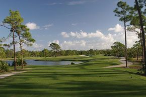 A golf course with trees and a lake in the background.