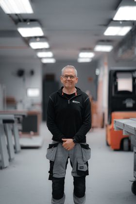A man is standing in a room with his hands on his hips.