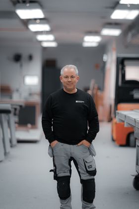 A man is standing in a room with his hands in his pockets.