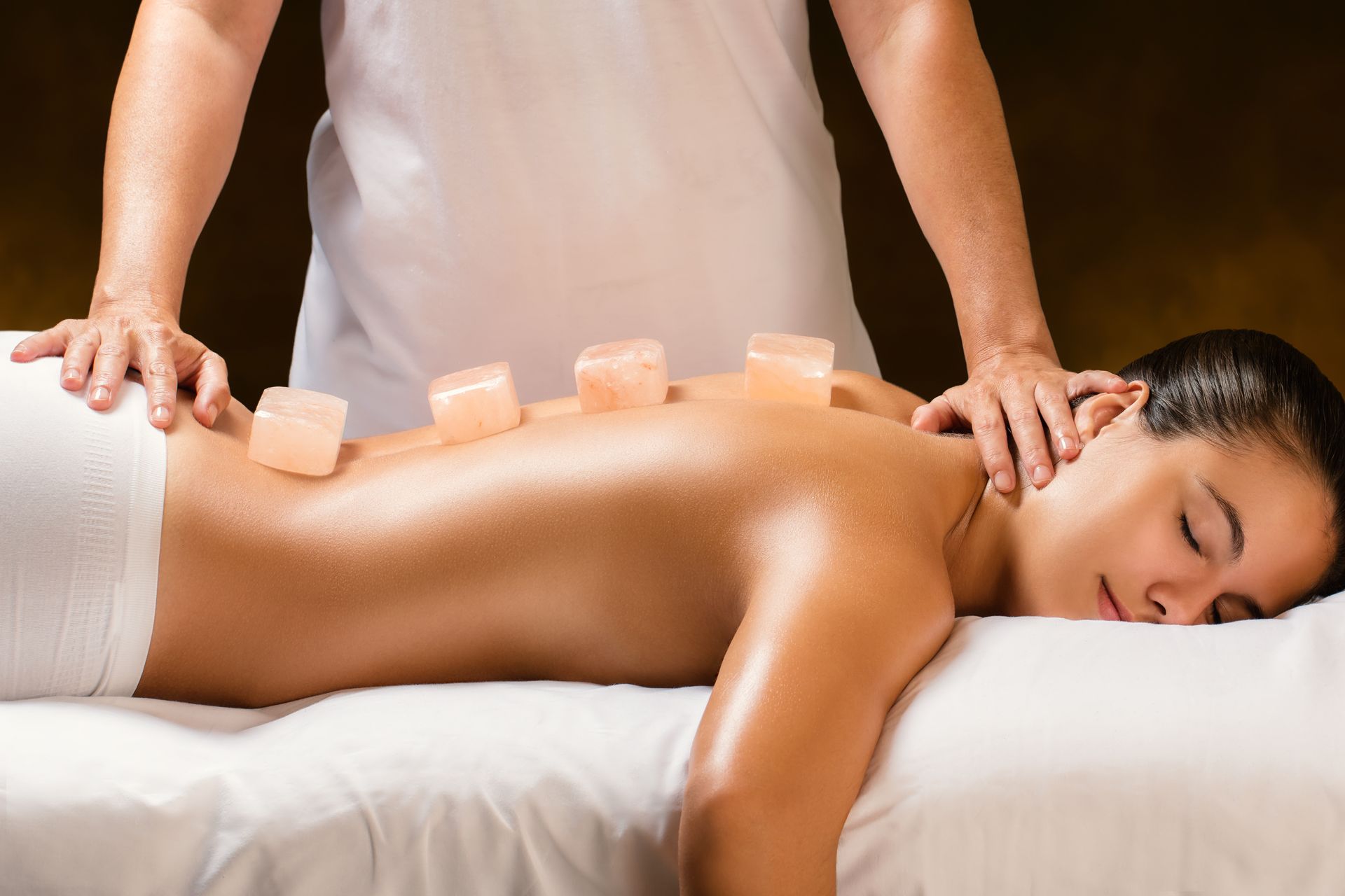 A woman is getting a massage with rocks on her back.