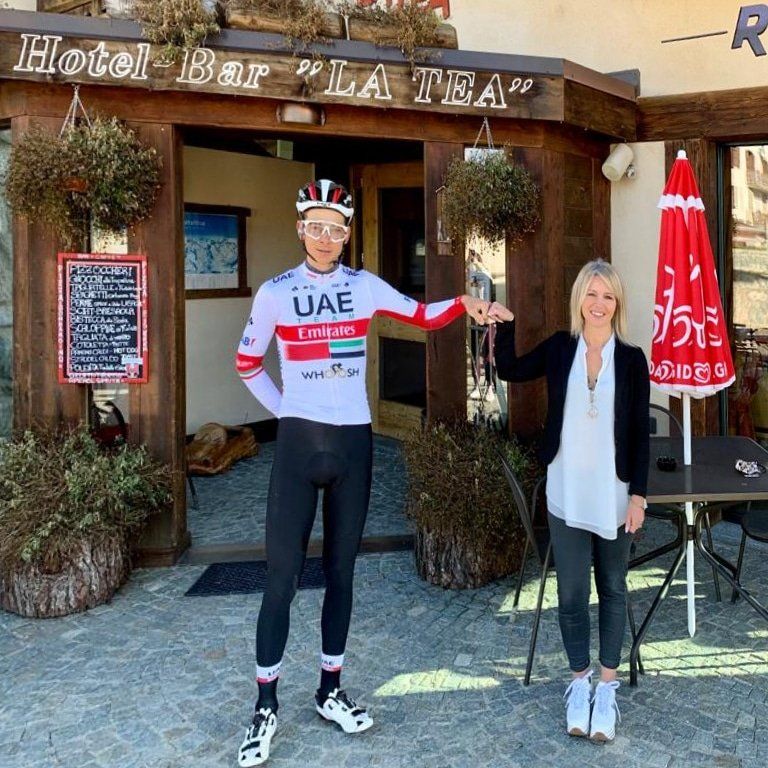 Un ciclista con la maglia della squadra e una donna fuori dall'hotel
