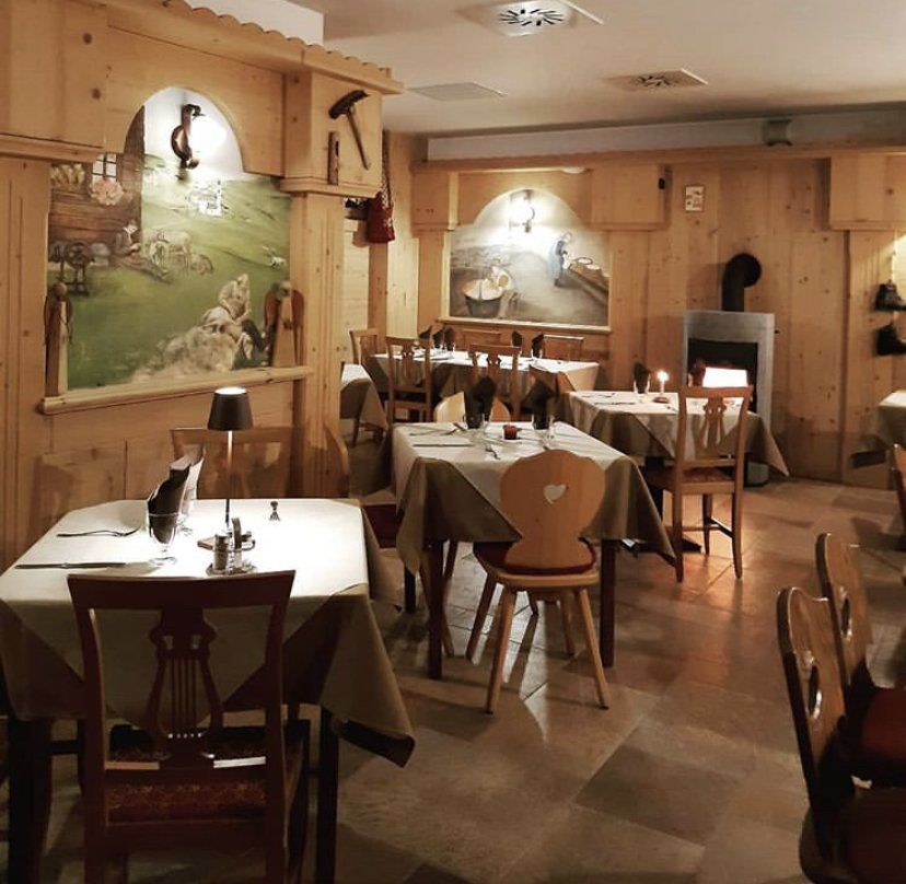 Interno del ristorante con pannelli in legno e tavoli apparecchiati per cenare.