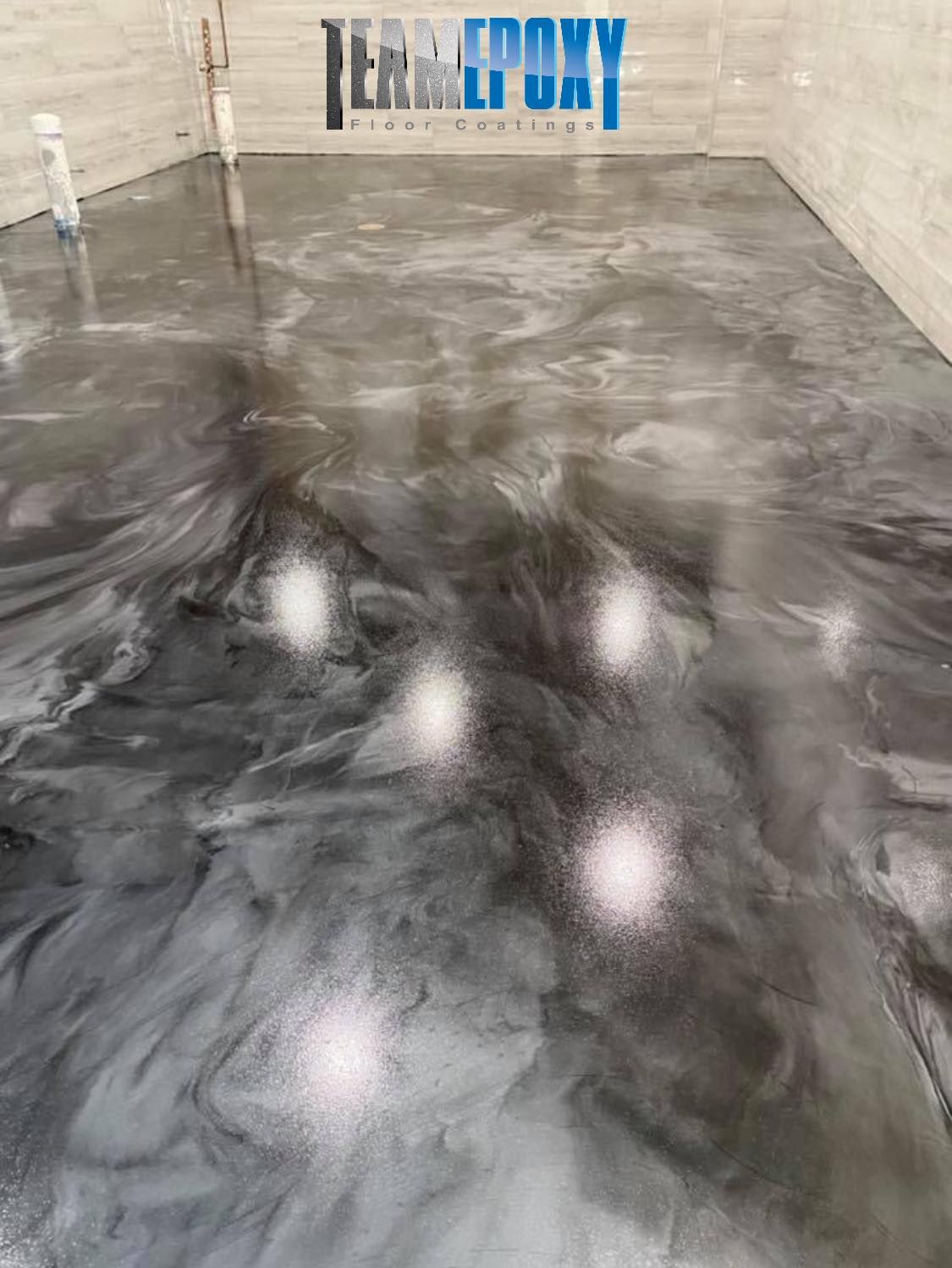 A gray and silver epoxy floor with a marbled effect. The floor reflects light, in a room with a 