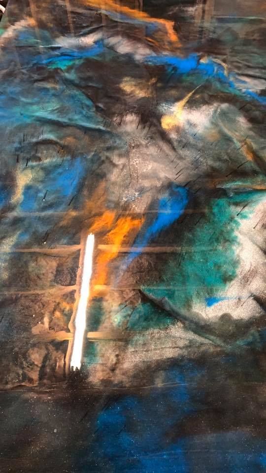 Abstract floor art with swirled blues, greens, blacks, and golds, resembling a landscape or water. Vertical light stripe.
