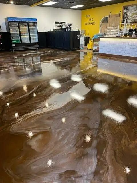 Shiny, brown and white swirled epoxy flooring in a brightly lit cafe, reflecting the interior and overhead lights.