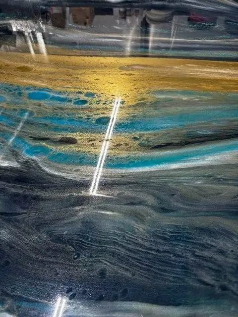 Abstract artwork with layered blue, gold, and gray colors. Two vertical white lines cut through the design.