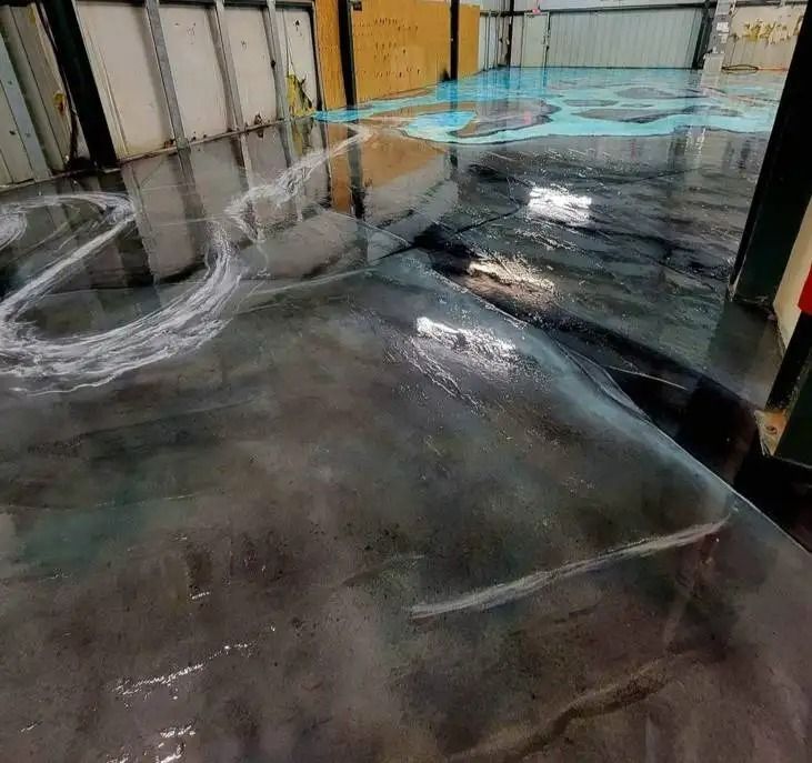 A metallic gray epoxy floor reflects light and a scattering of what appears to be a cleaner or residue.
