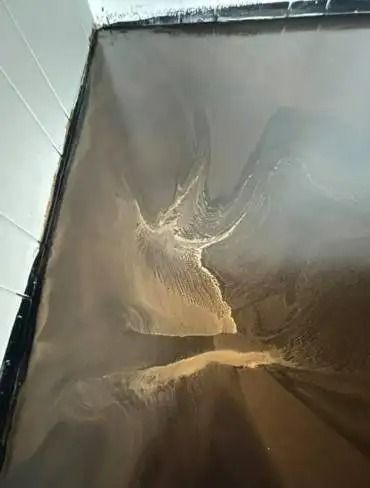 A dark brown epoxy floor with abstract light brown swirls. The floor meets a white wall in a corner.