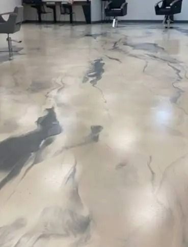 Shiny, light-colored epoxy floor with marbled gray and black veining in a hair salon. Several salon chairs are visible.