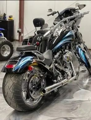 Black and blue custom motorcycle with a wide rear tire, chrome accents, and a black seat in a garage.