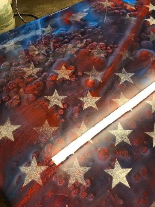 A patriotic American flag with silver stars and red and blue background. A white strip is laid across the flag.