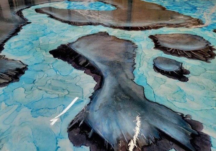 Epoxy flooring with a water and island design, featuring blue and gray tones. The glossy surface reflects light.