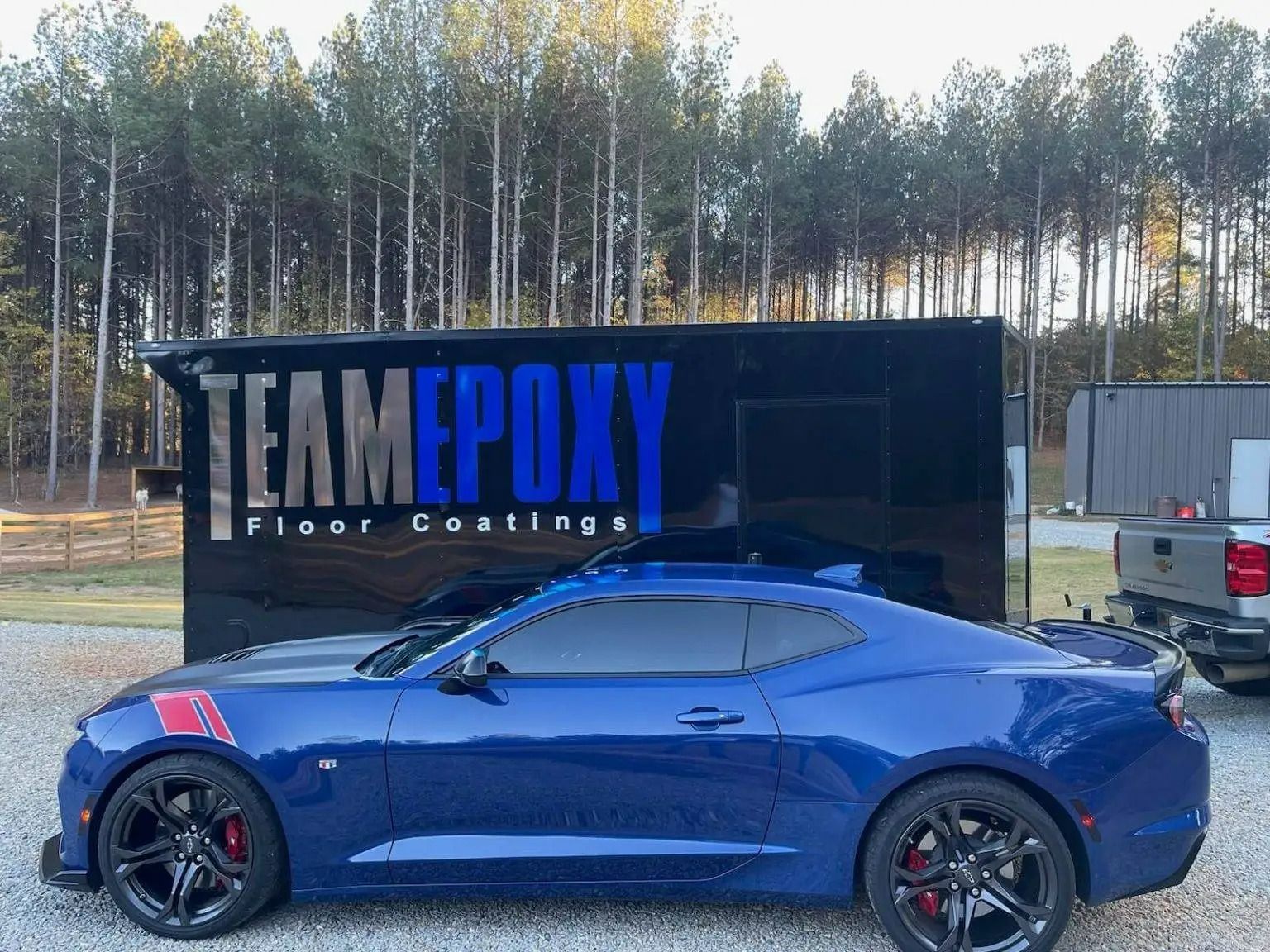 Blue Camaro with red stripes in front of a trailer for