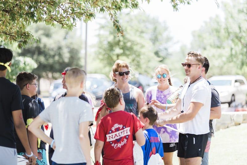 Group of adults and children in a parking lot.