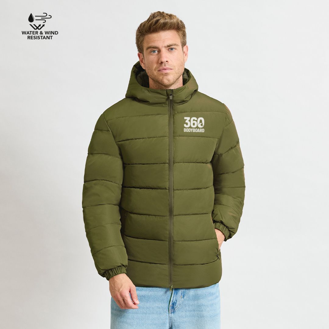 Homem vestindo uma jaqueta puffer verde com capuz, em pé contra um fundo branco.